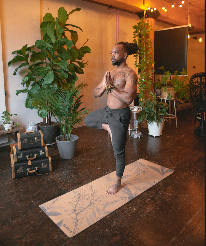 Man practicing yoga in a room with plants and furniture