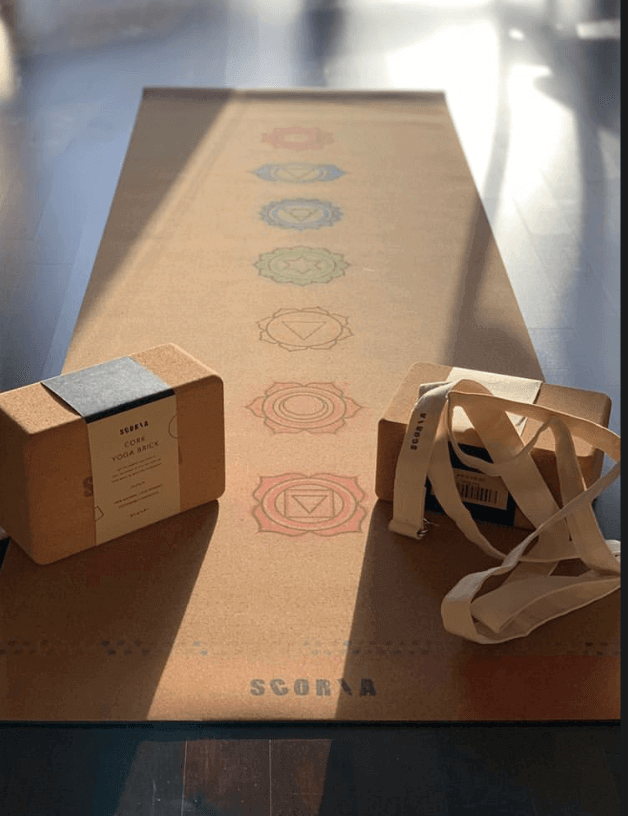 Yoga mat with chakra symbols, yoga block, and strap on a reflective surface
