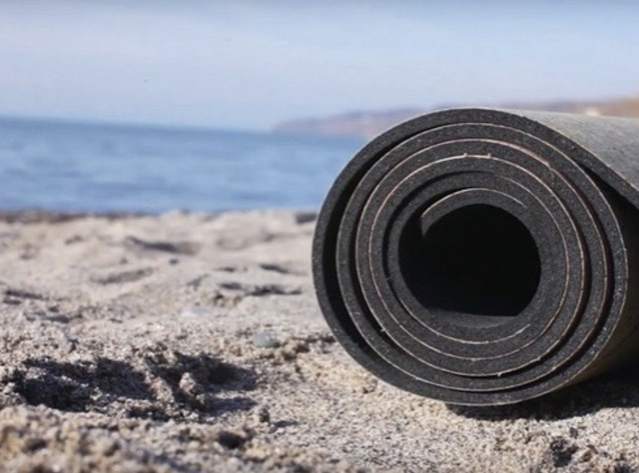 rolled-up cork yoga mat on a beach