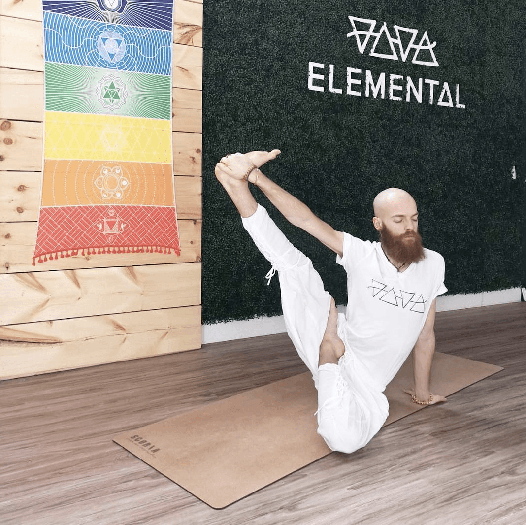 Person practicing yoga on a cork yoga mat in a room with  branding on the wall.