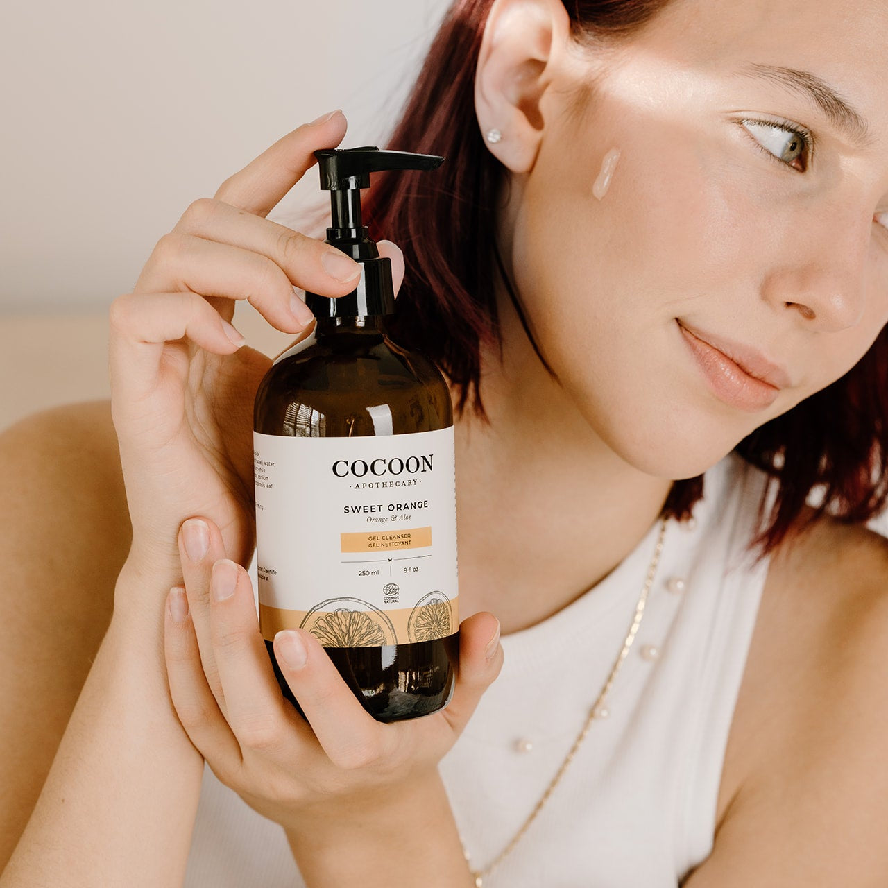Woman holding a bottle of Cocoon Sweet Orange Gel Cleanser 