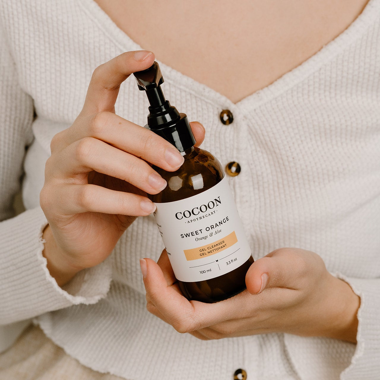 Person holding a bottle of Cocoon Sweet Orange gel cleanser.