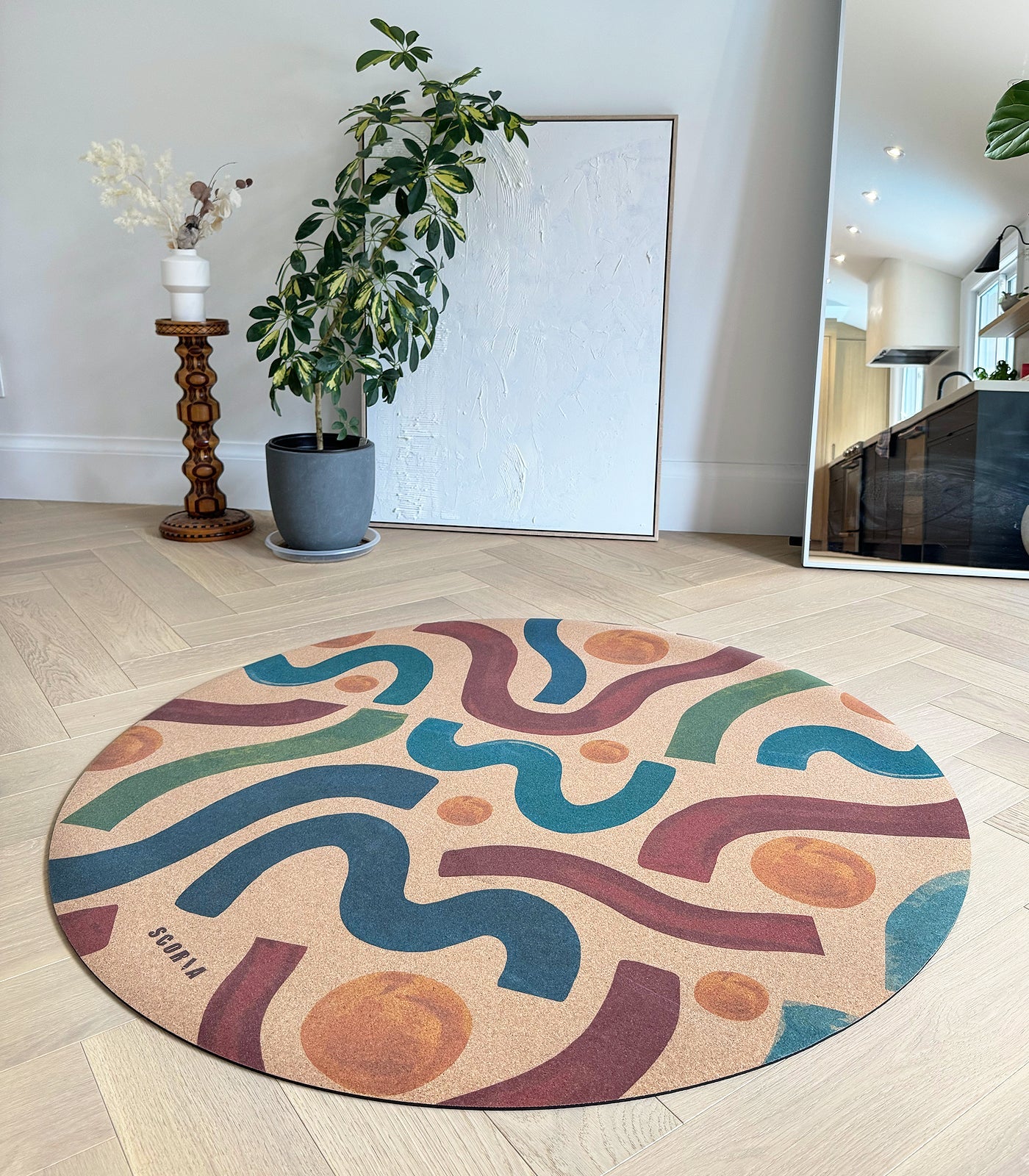Round cork yoga mat with colorful wavy pattern in  a studio with a large mirror