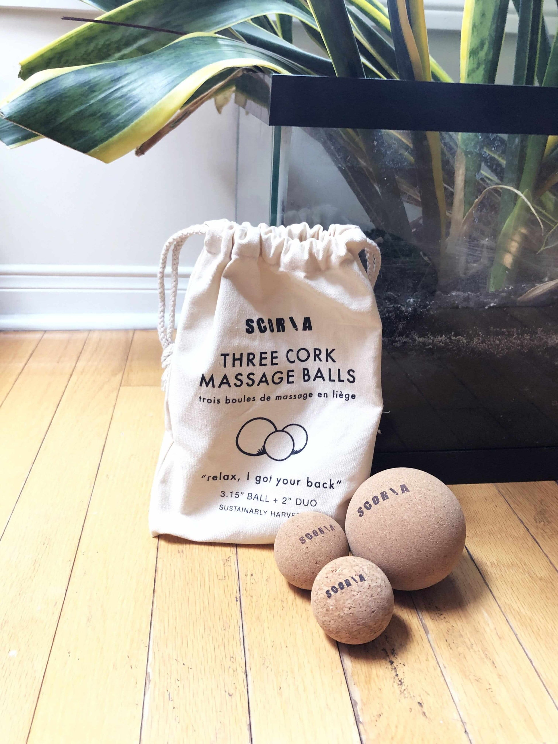 set of 3 cork massage balls in front of a bag on a wooden floor setting