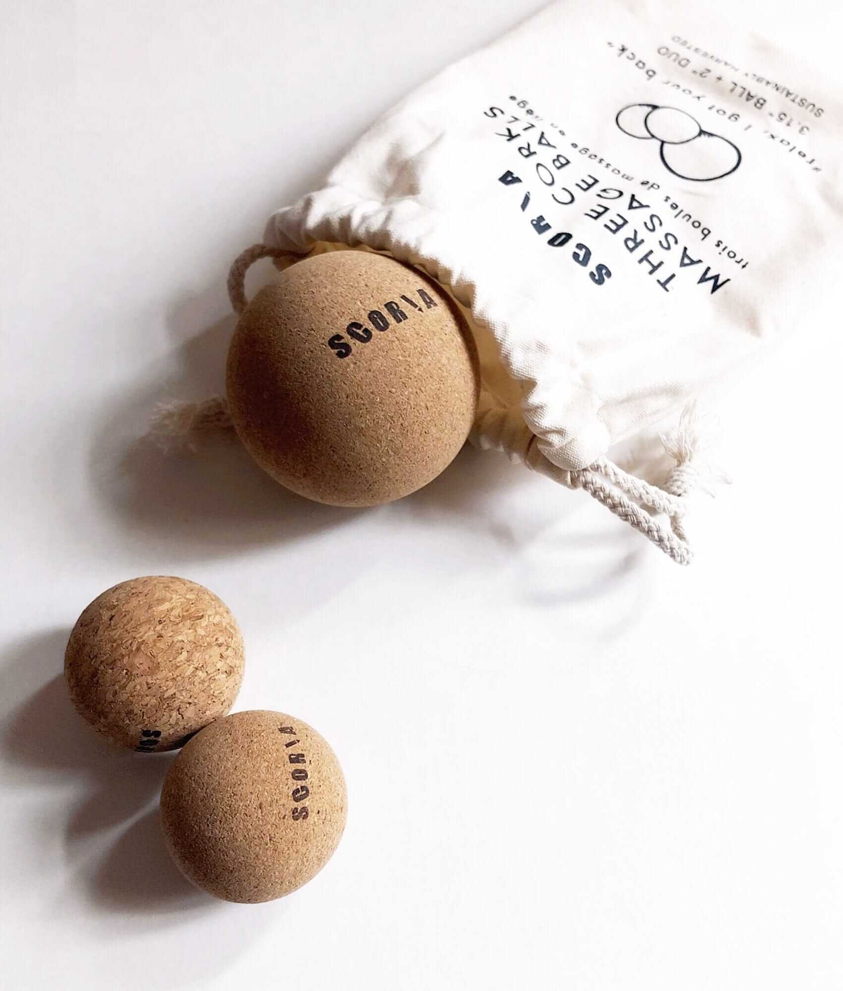 Cork balls with  branding on a white surface, next to a drawstring bag with brand name.