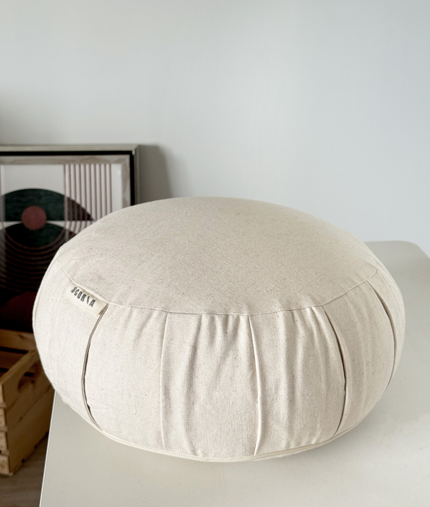Round beige meditation pillow on a white surface with a neutral background
