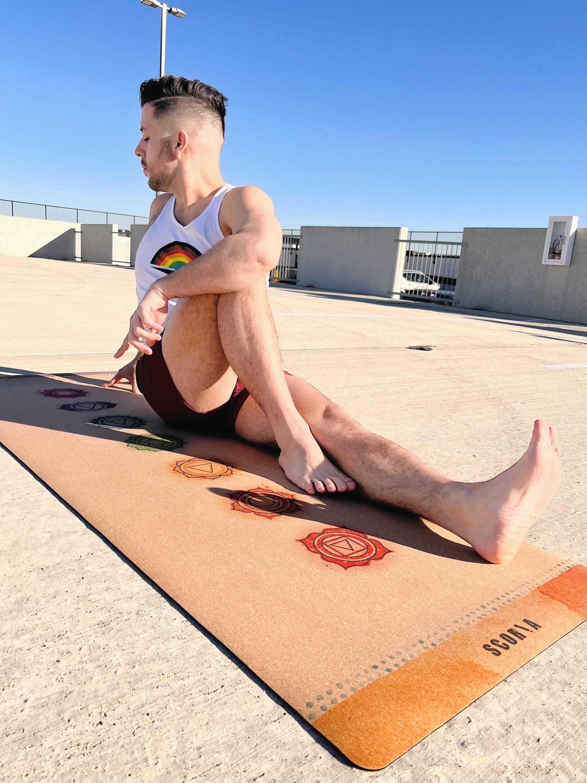 Person sitting on a Cork yoga mat with chakra symbols outdoors