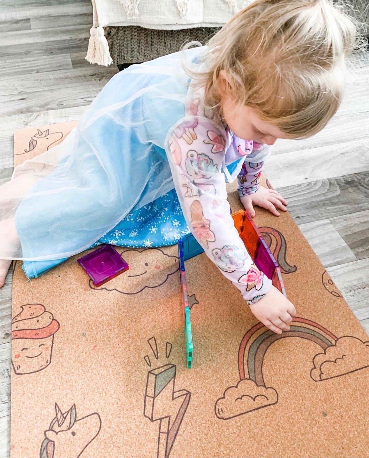 child playing on a kids' cork yoga mat with unicorn and rainbow pattern
