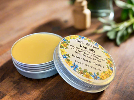 Tin of Back Kitchen Remedy Salve on a wooden surface with a label featuring floral designs.