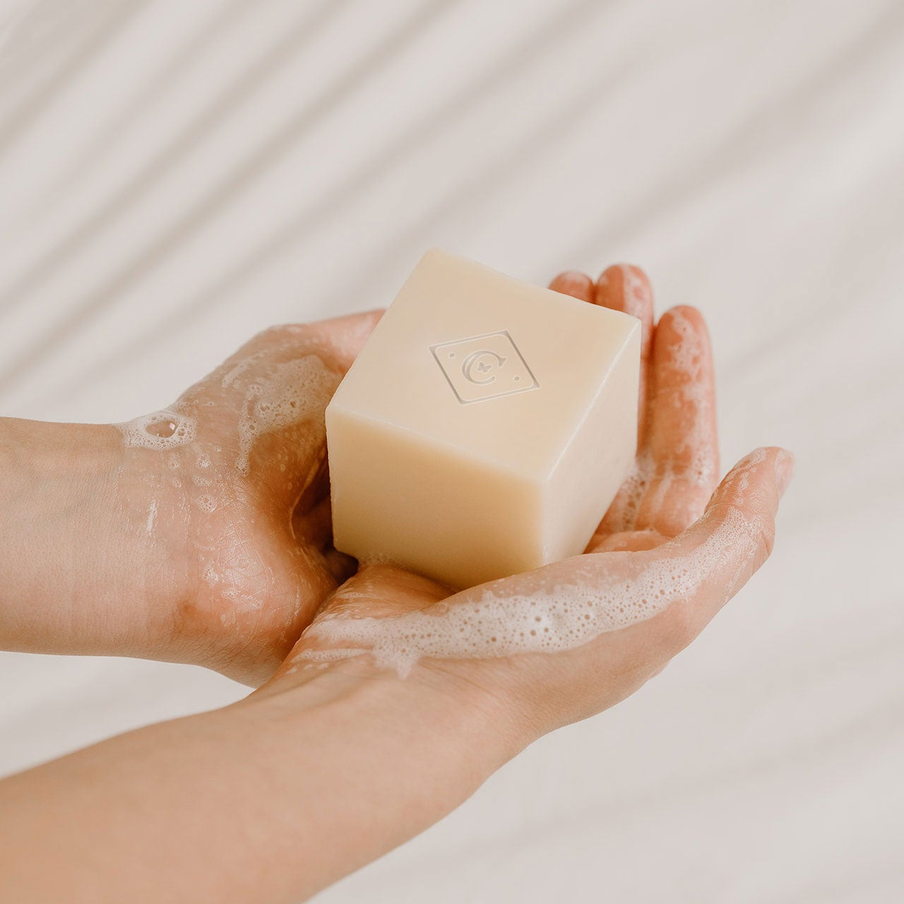 Hands holding a bar of soap with a light background
