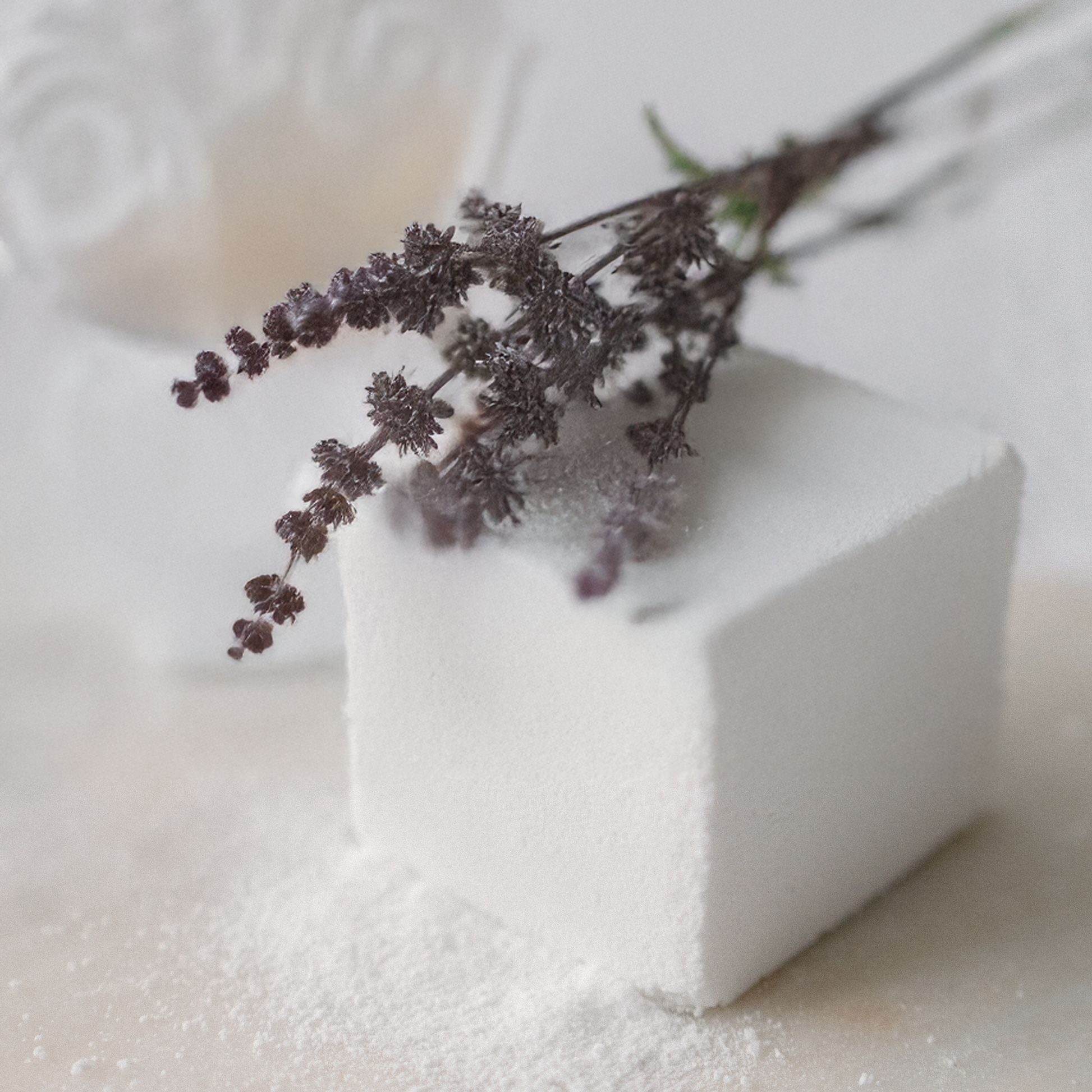 White Patchouli Vibes Bath Cube with a branch of dried lavender on a white background