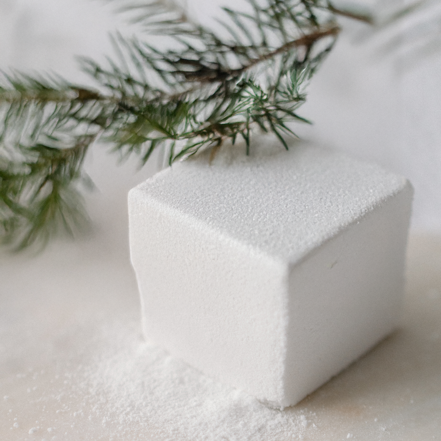 Spruce Flora  Bath Cube on a white surface with a branch in the background