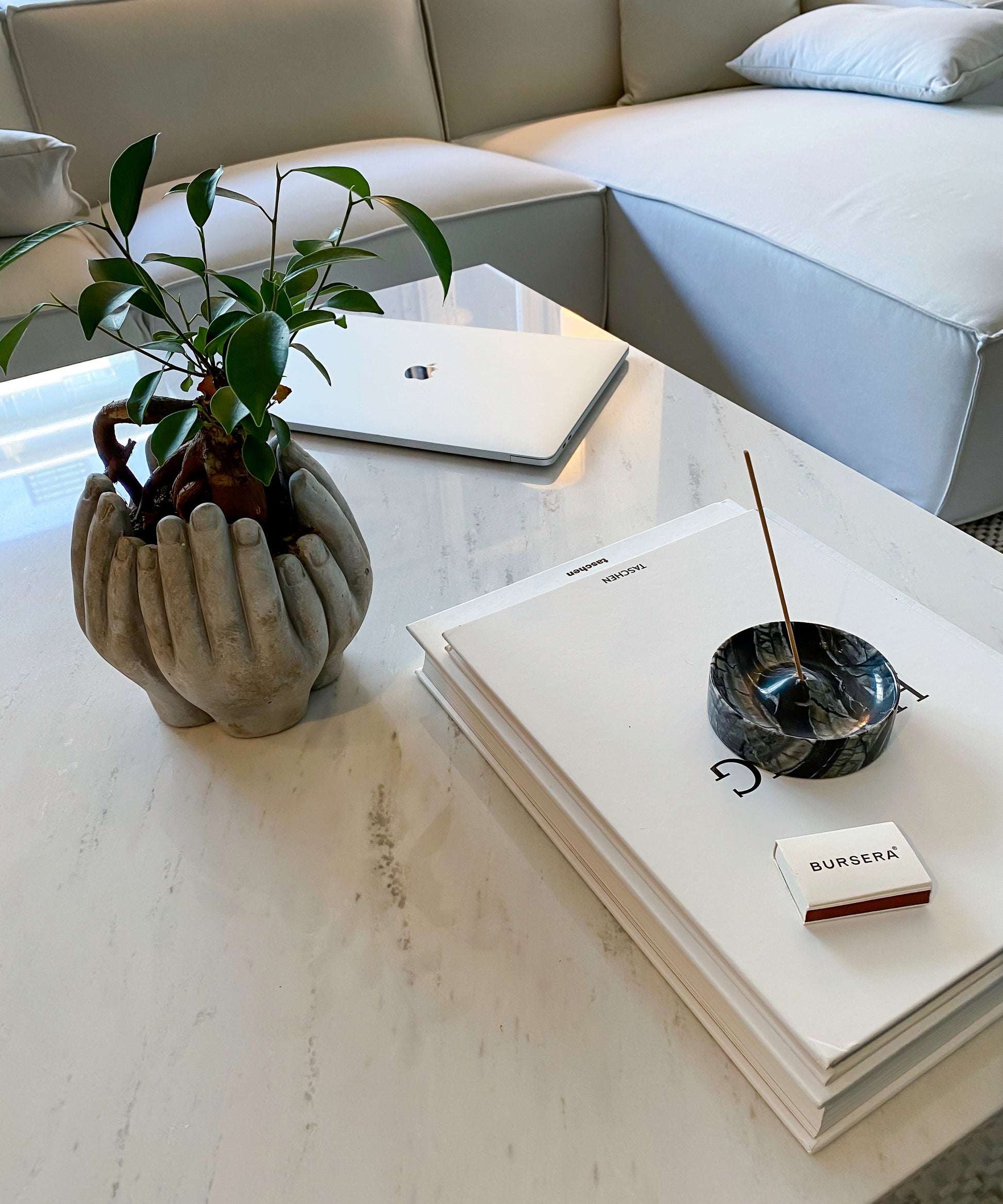 black marble incense holder aromatherapy decor in a modern living room with a coffee table featuring a plant, laptop, and books.