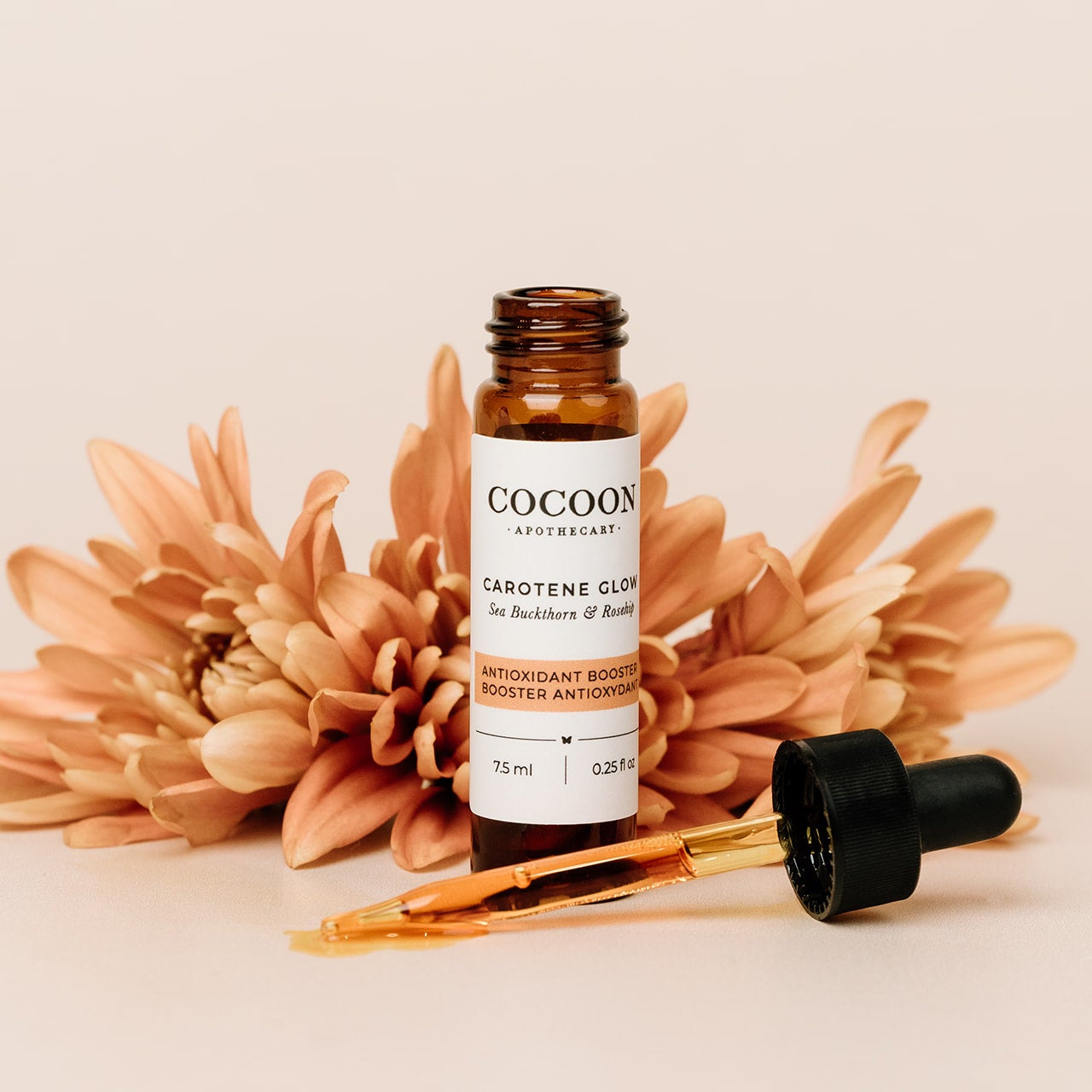 Cocoon skincare Carotene Glow Antioxidant Booster bottle with dropper on a beige background