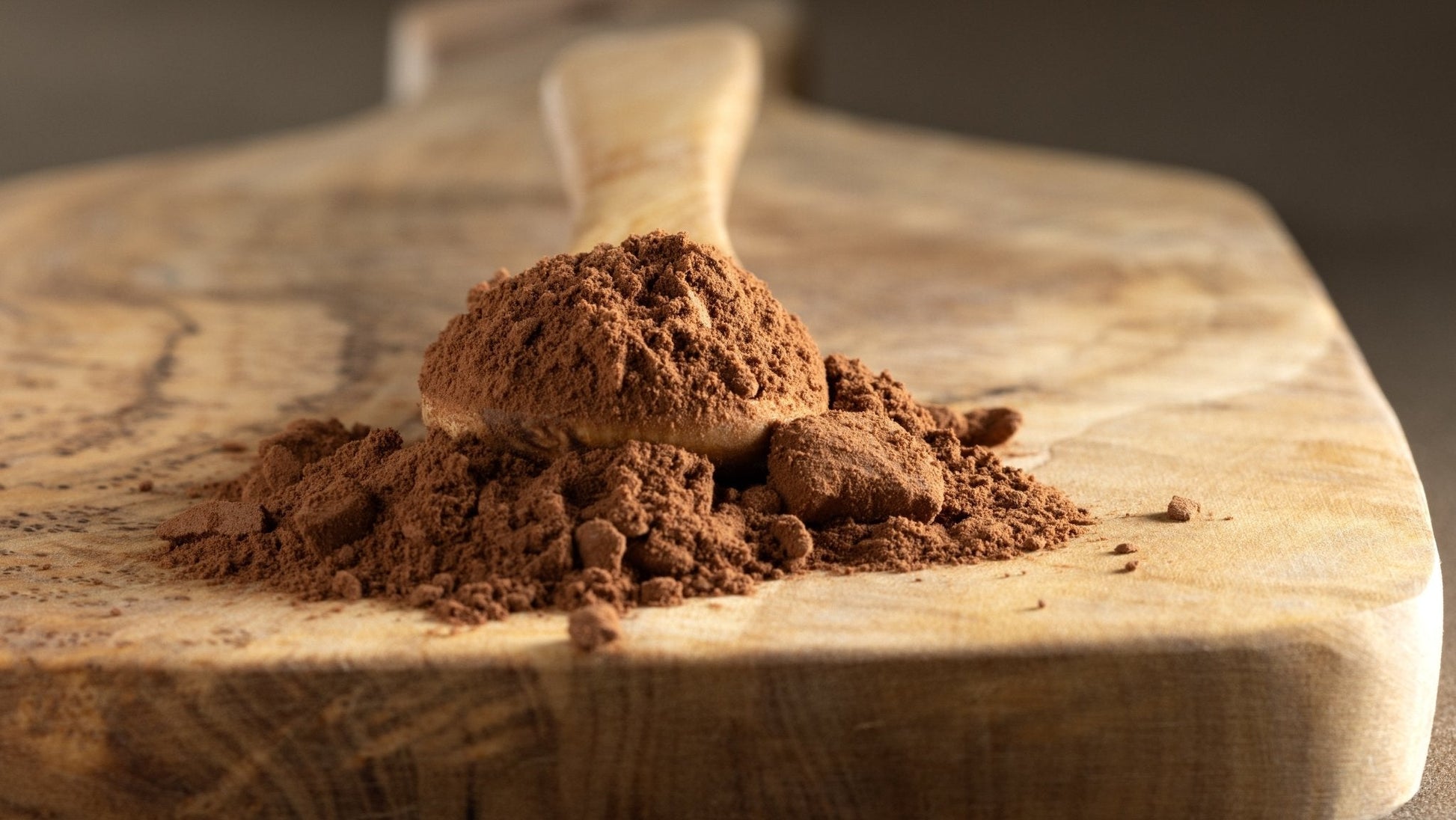 Cocoa powder on a wooden spoon and cutting board