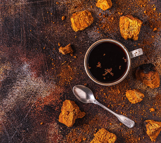 Cup of changa powder tea with a spoon on a rustic wooden surface with coffee grounds.