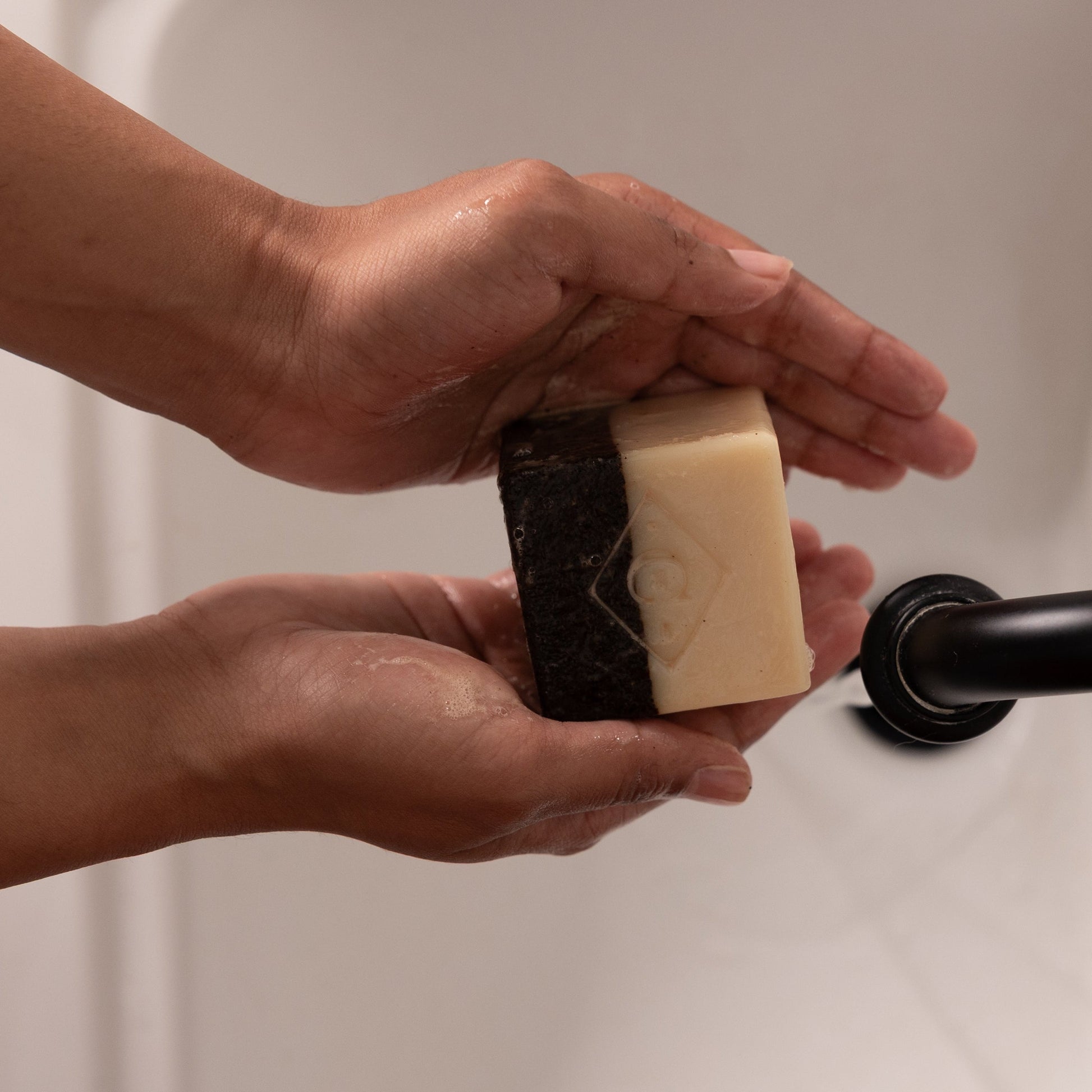 Person holding a bar of Coffee Scrub Bar Soap over a sink