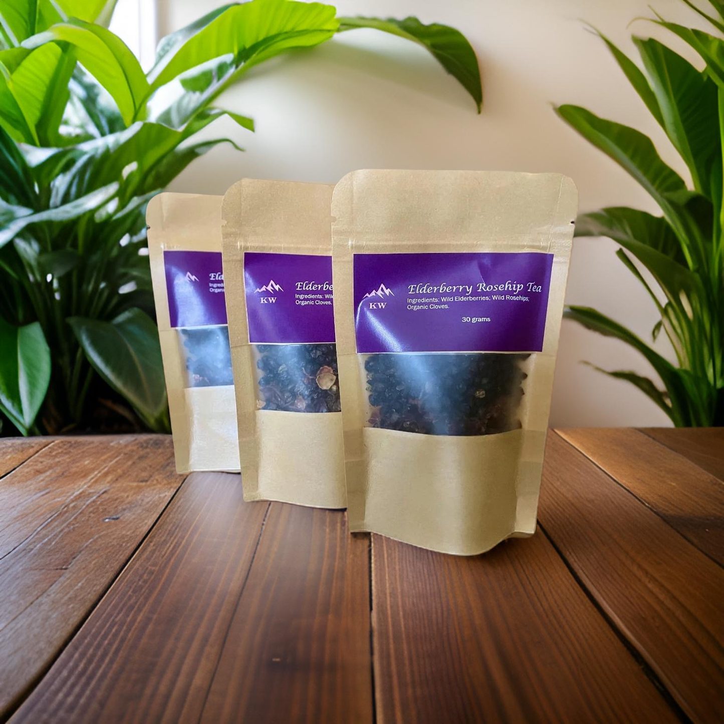 Three packages of Elderberry Roselle Tea on a wooden surface with plants in the background