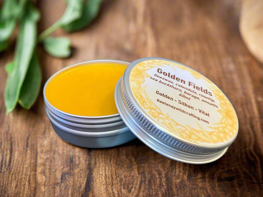 Yellow Golden Fields Skin Salve balm in a tin with a visible brand label on a wooden surface