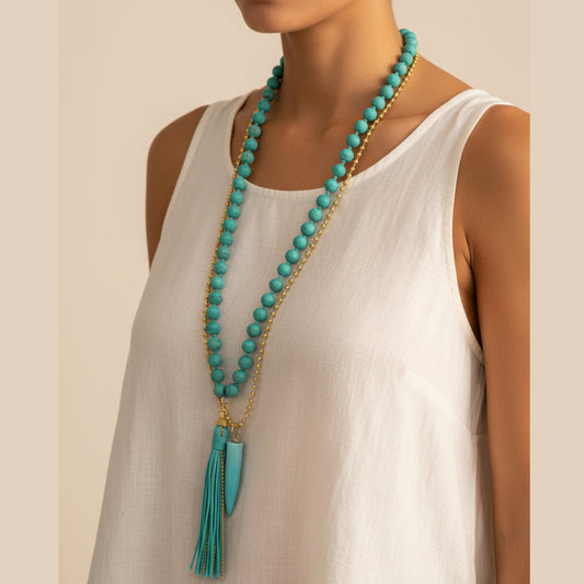 Long layered necklace with large turquoise round beads, gold ball chain, turquoise horn pendant and turquoise leather tassel worn by a woman — handmade in India for boho and statement style
