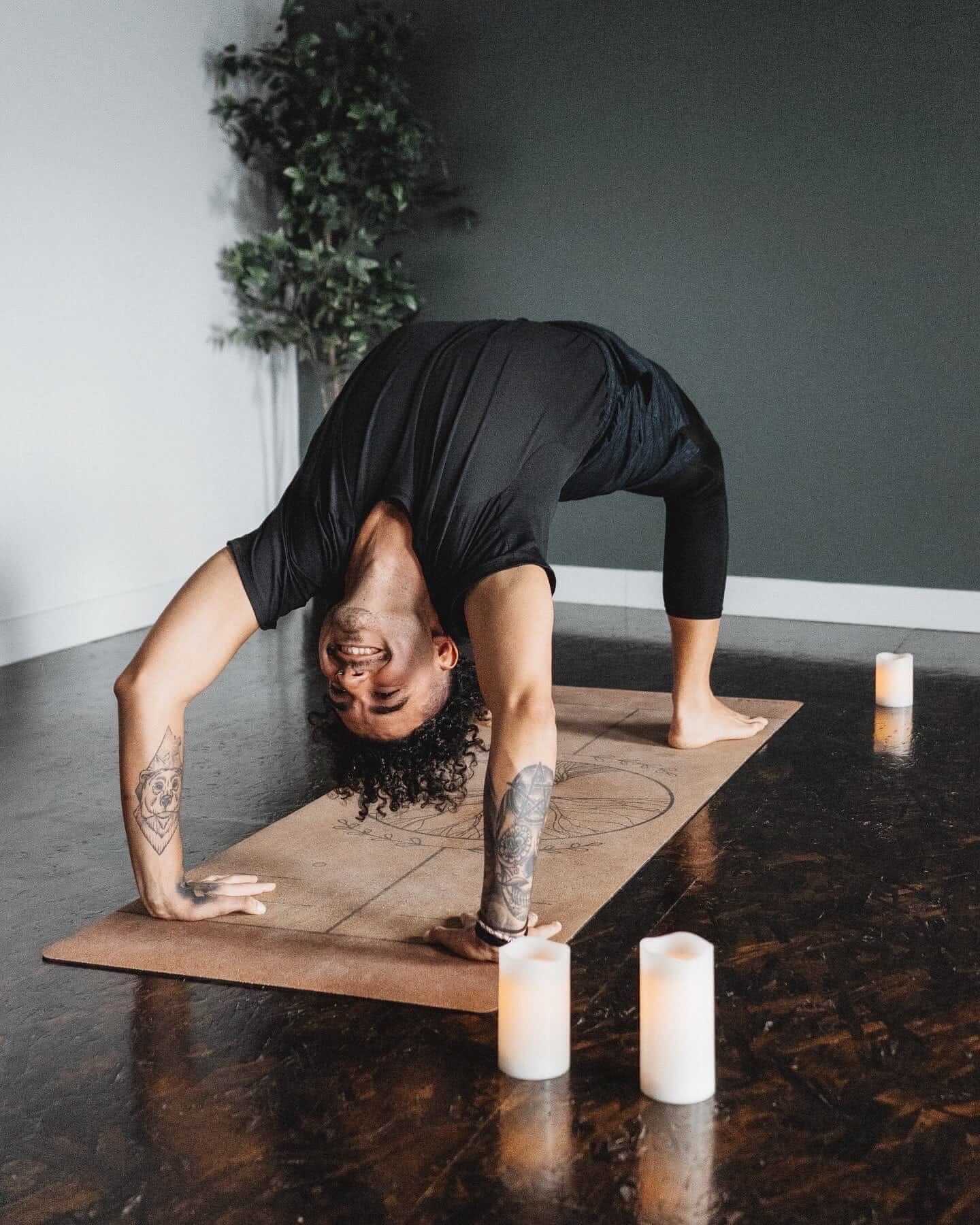 Person performing a yoga pose on a extra thick cork yoga mat with candles and plants in the background