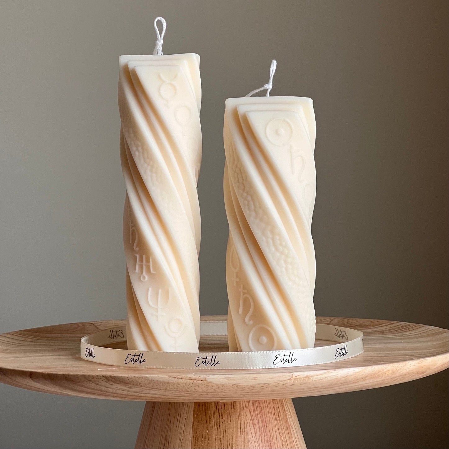 two astrological soy pillar candles in beige color on display