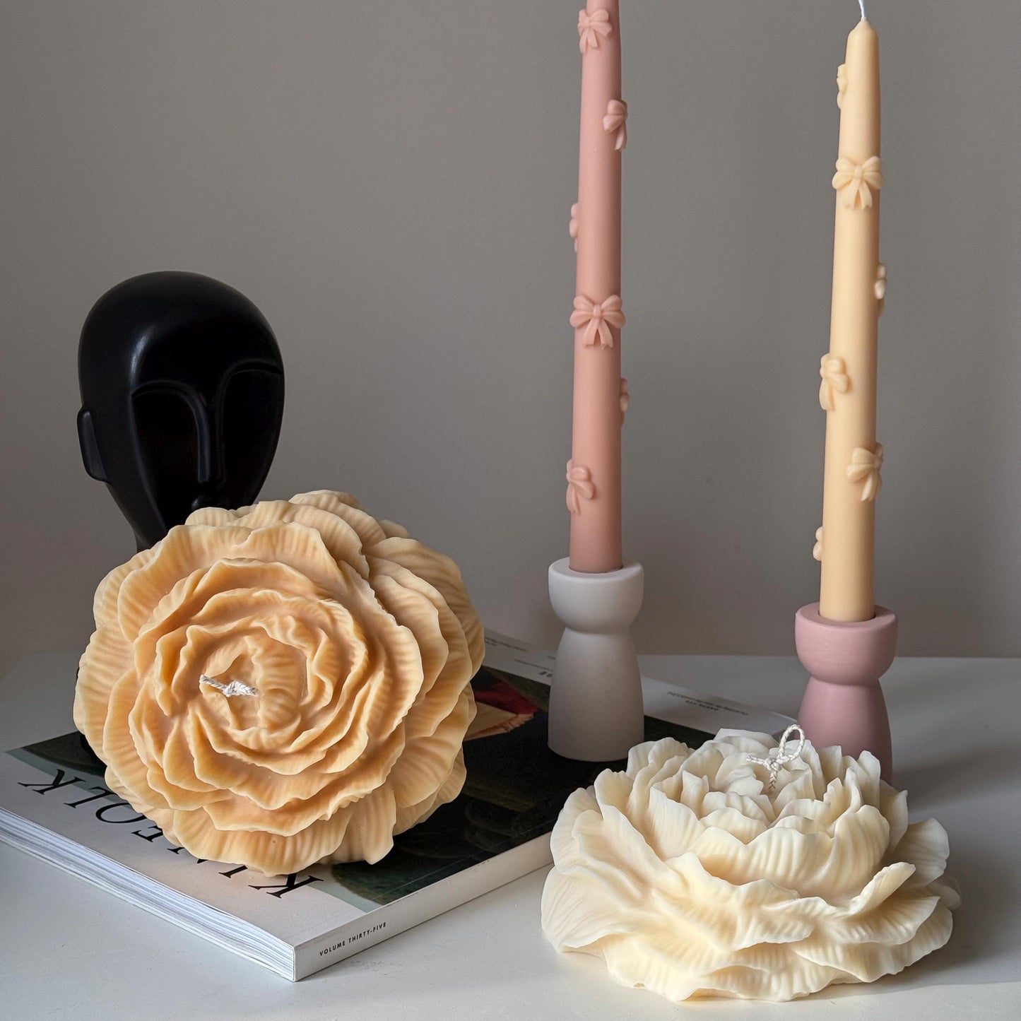 Large peony soy pillar candle in mellow and cream colors on display