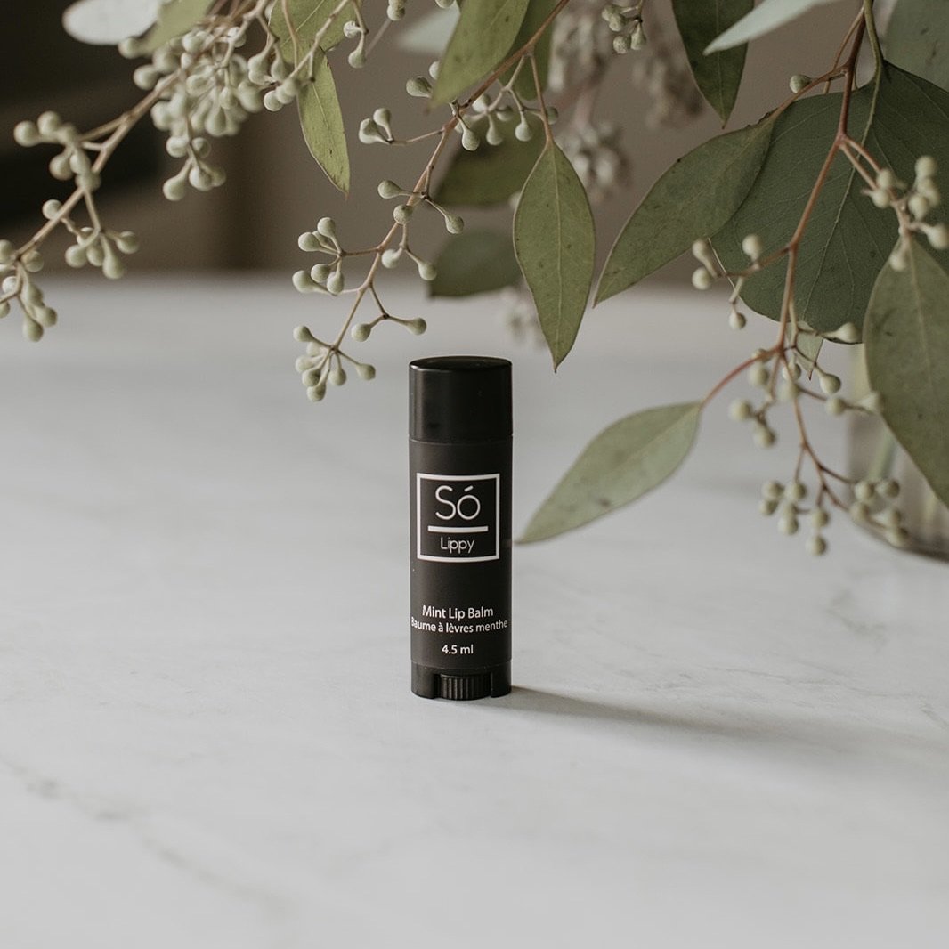 Mint lip balm with 'Sö Lippy' branding on a light surface with greenery in the background