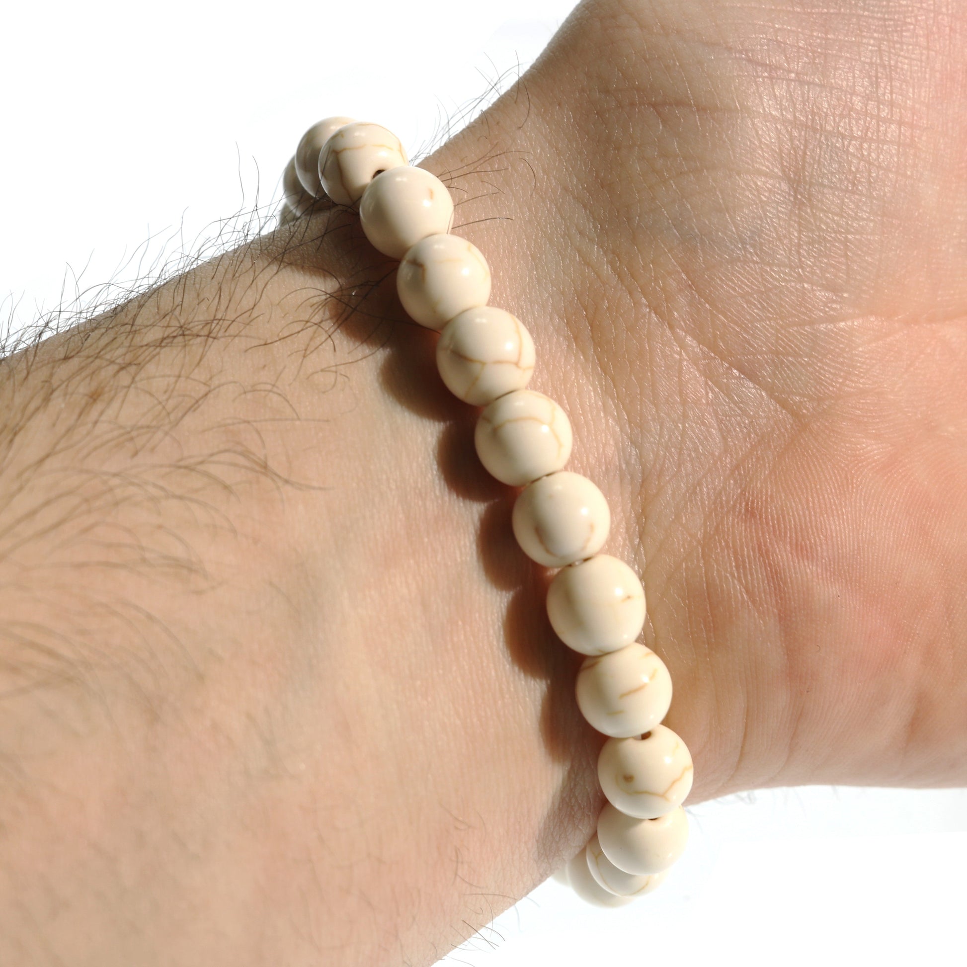 Beaded white Howlite bracelet on a wrist against a white background