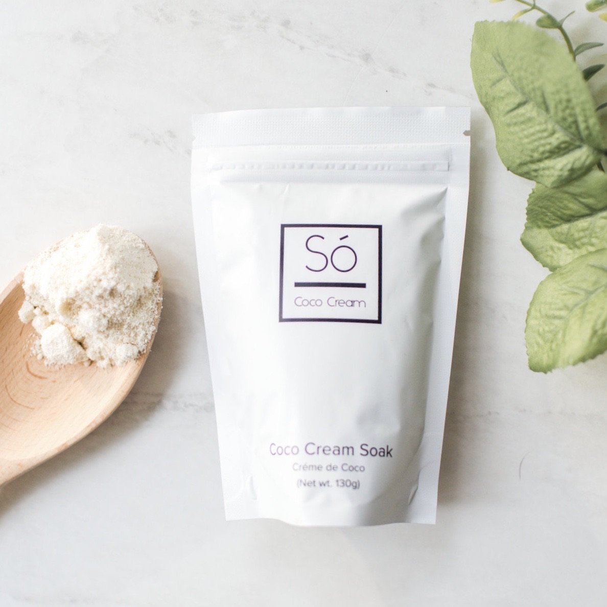 Coco Cream Soak packaging with a wooden spoon and green leaves on a light background