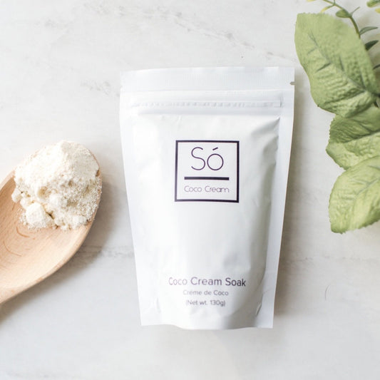 Coco Cream Soak packaging with a wooden spoon and green leaves on a light background