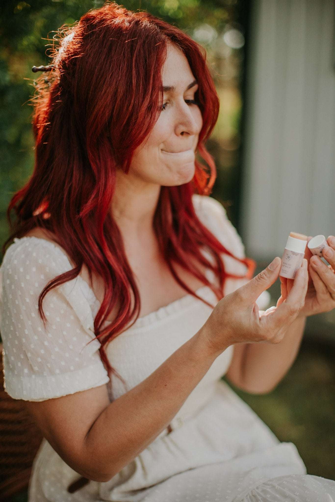 Woman with red hair applying lip balm outdoors
