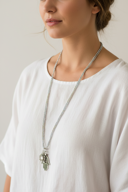 Long double-strand silver seed bead necklace with antique silver charm and ornate Hamsa hand pendant worn by a woman — handmade in India for boho, spiritual, and protective style