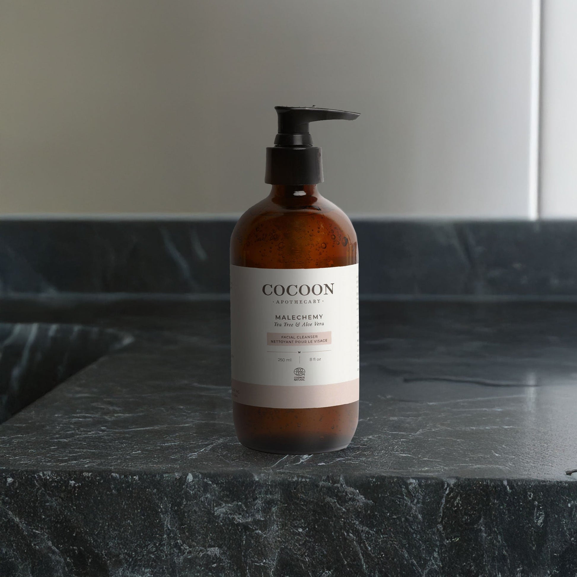 Cocoon bottle of facial cleanser on a dark marble surface with a neutral background