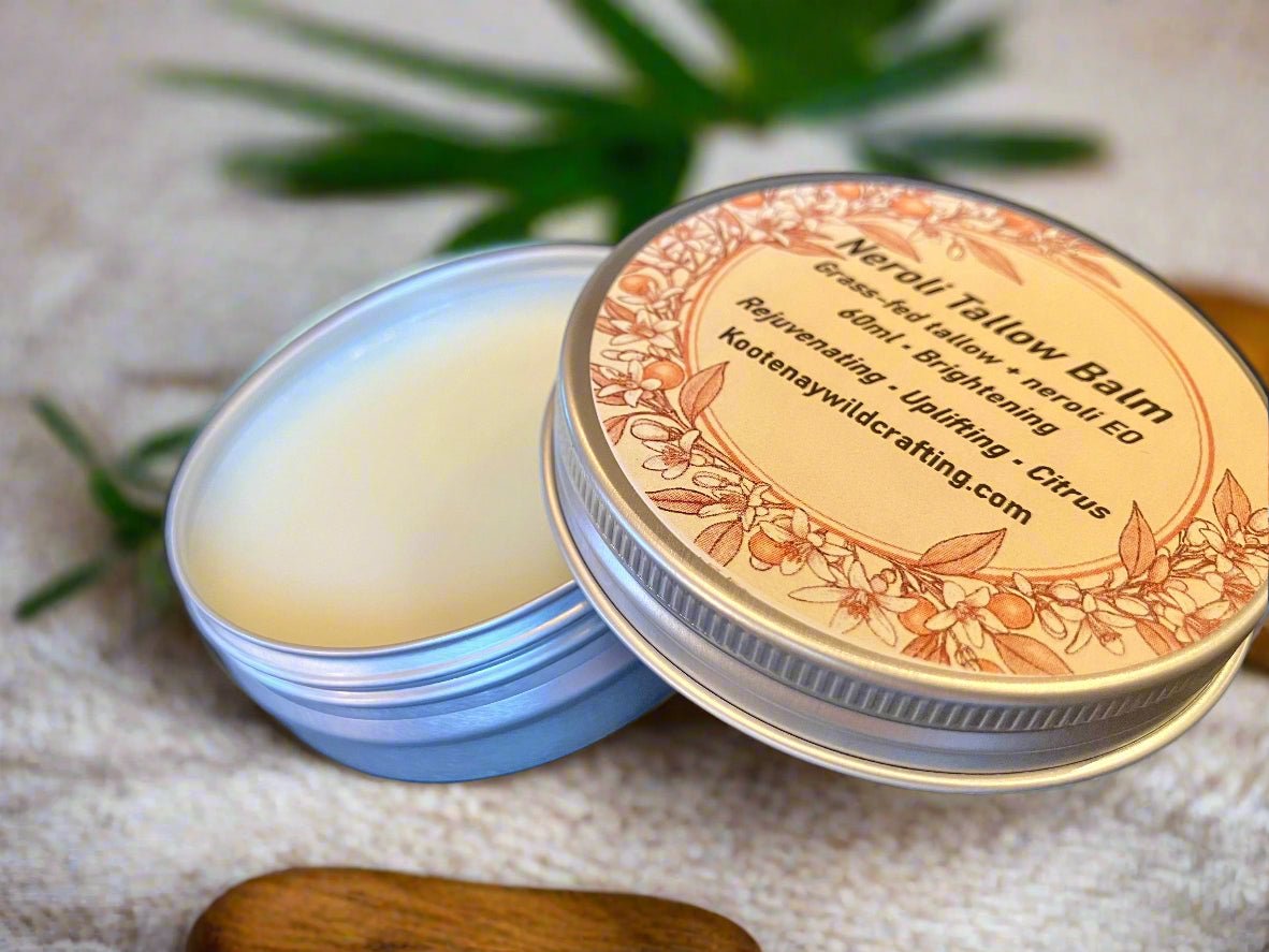 Neroli Tallow Balm tin with decorative label on a textured surface with green leaves.
