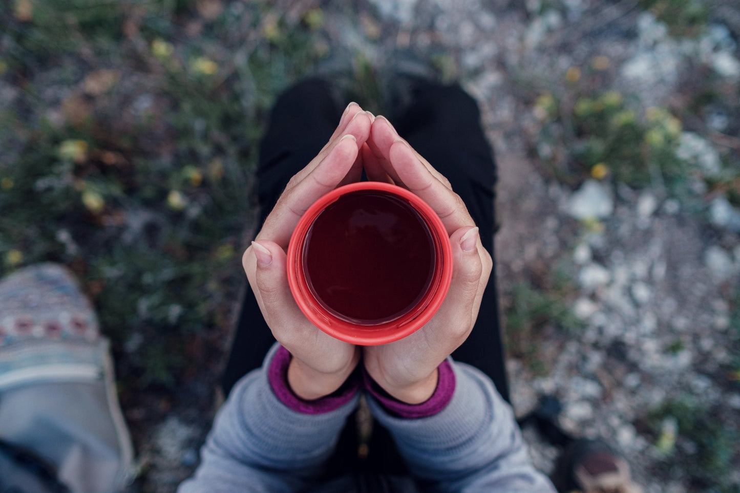 Person holding a red cup of changa coffee with a natural outdoor background