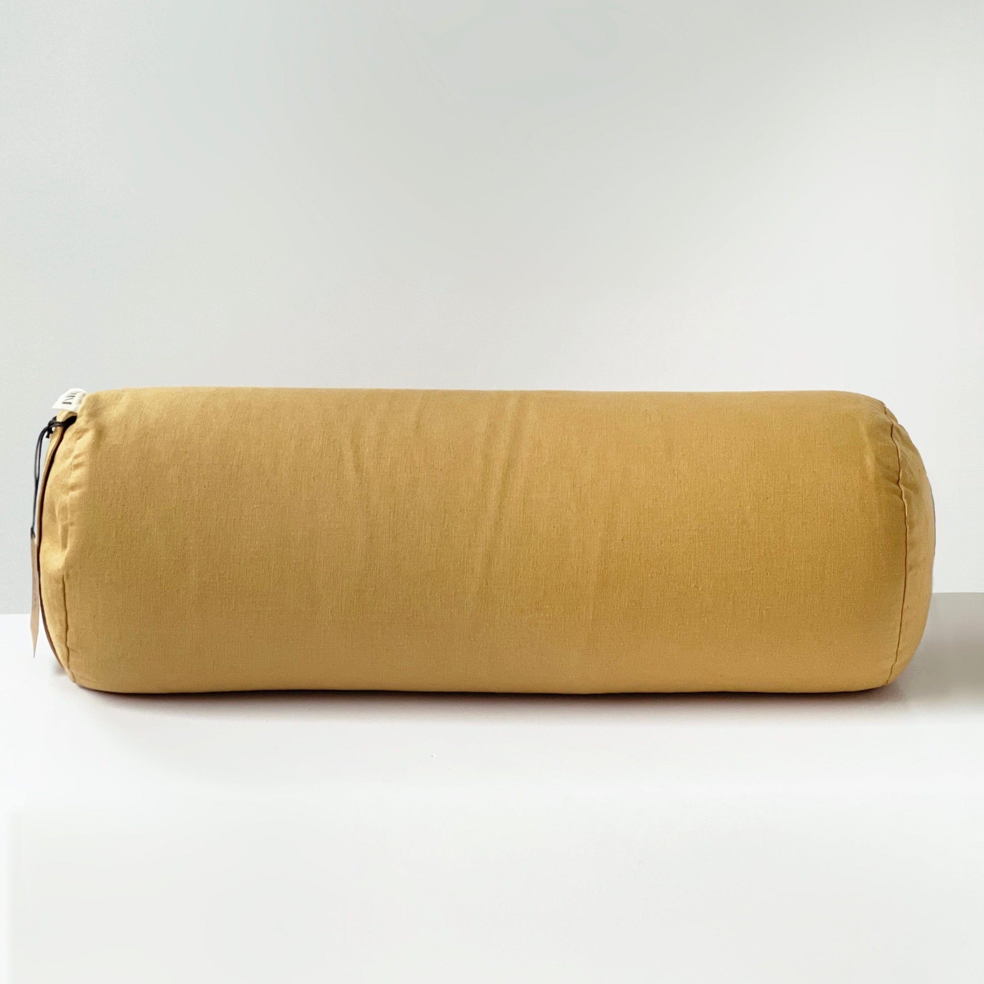 Gold yoga bolster cylindrical pillow on a white background