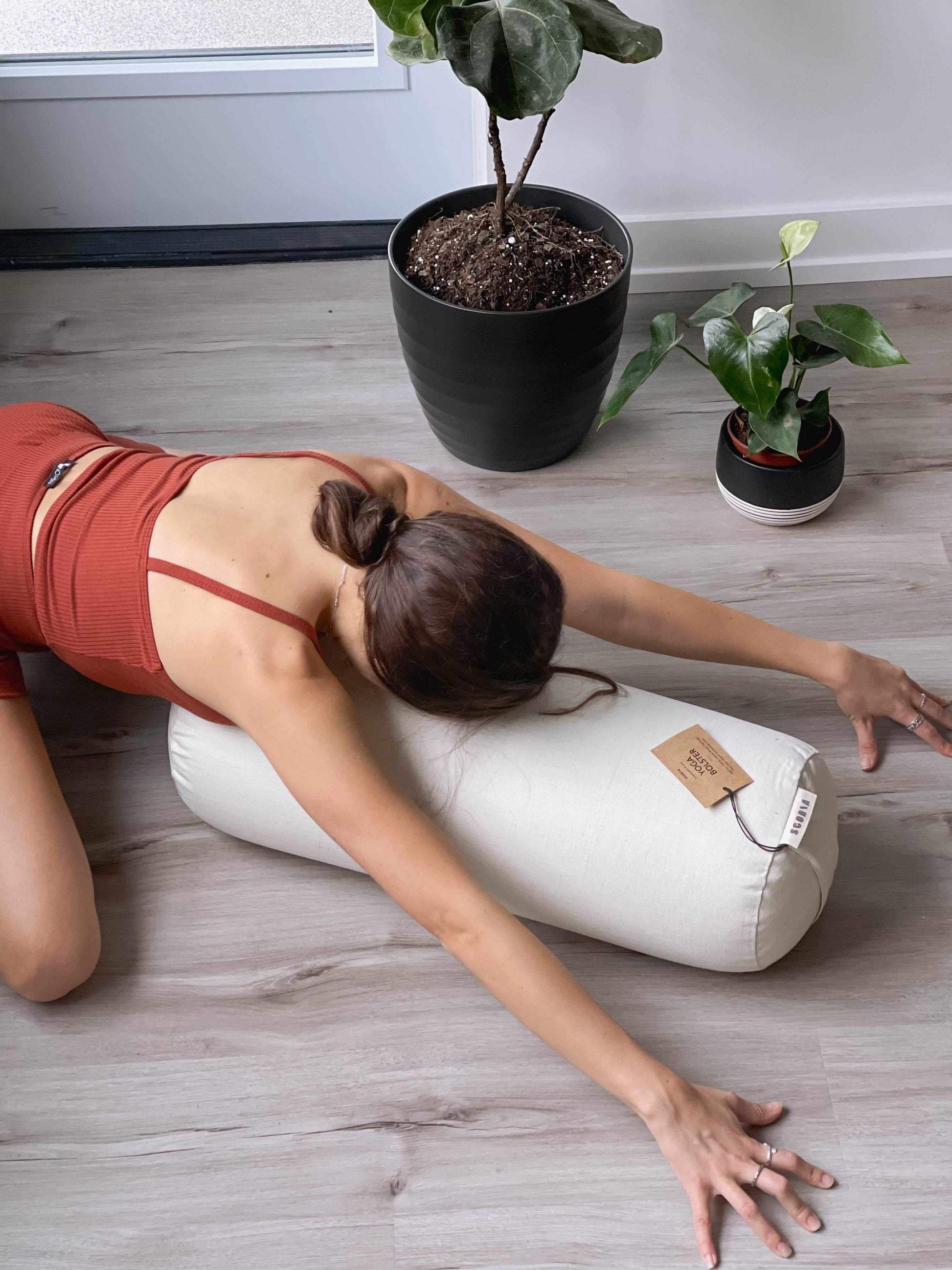 Woman lying on a white yoga bolster with plants in the background