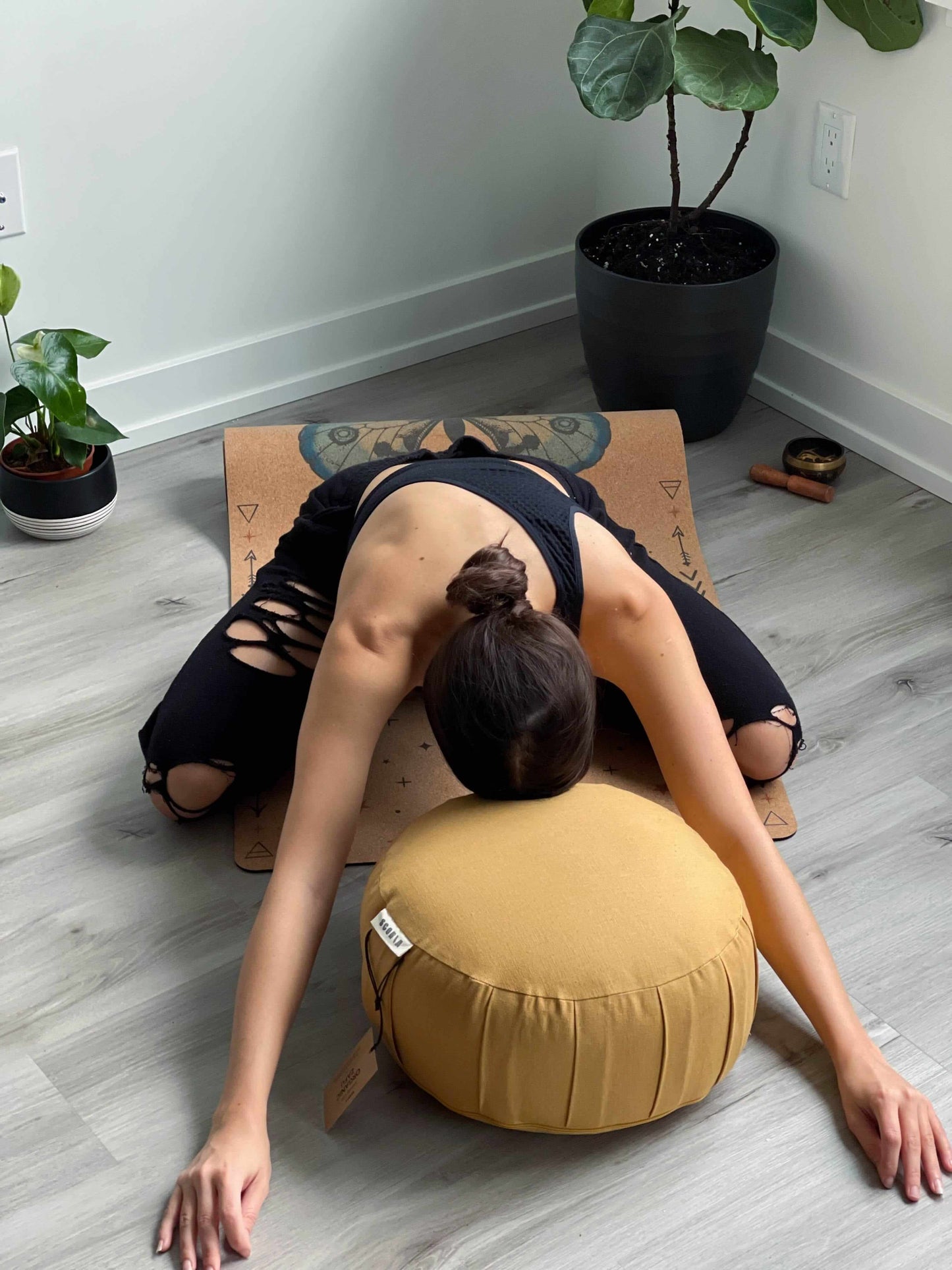 woman doing yoga with her head on a yellow meditation and yoga pillow