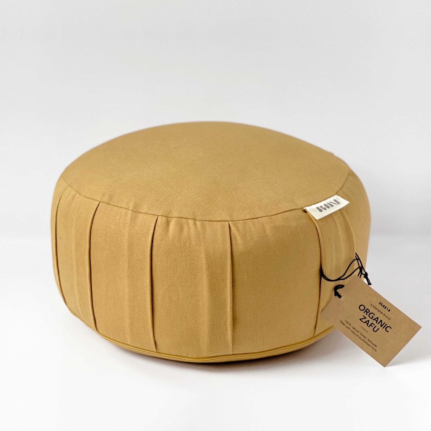 Round mustard-colored cushion with a tag on a white background