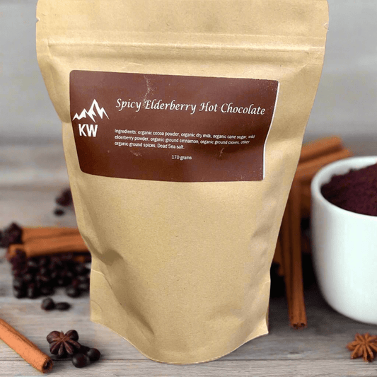 Spicy Elderberry Hot Chocolate package with a brown label, surrounded by cinnamon sticks and star anise on a wooden surface.