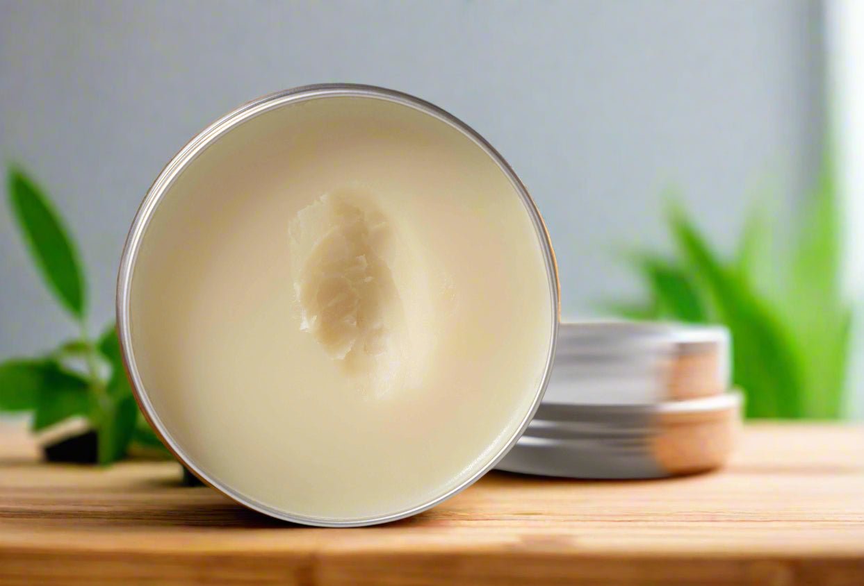 Metallic container with a Pure Tallow Balm on a wooden surface with greenery in the background