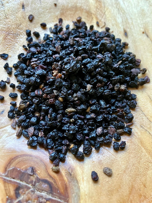 Pile of dark elderberries on a wooden surface