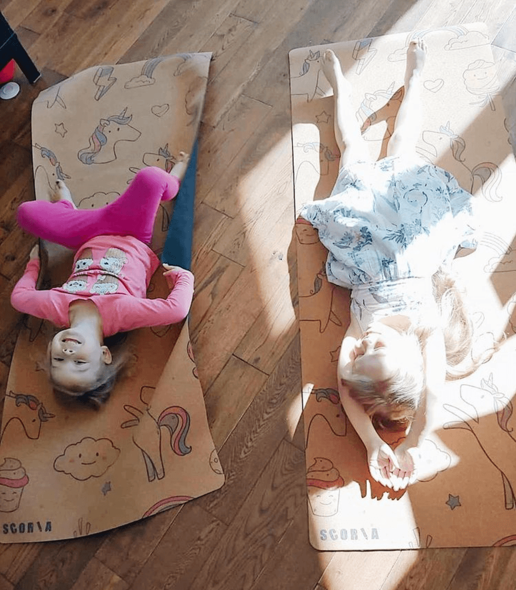 two children playing on kids' cork yoga mats with unicorn and rainbow patterns