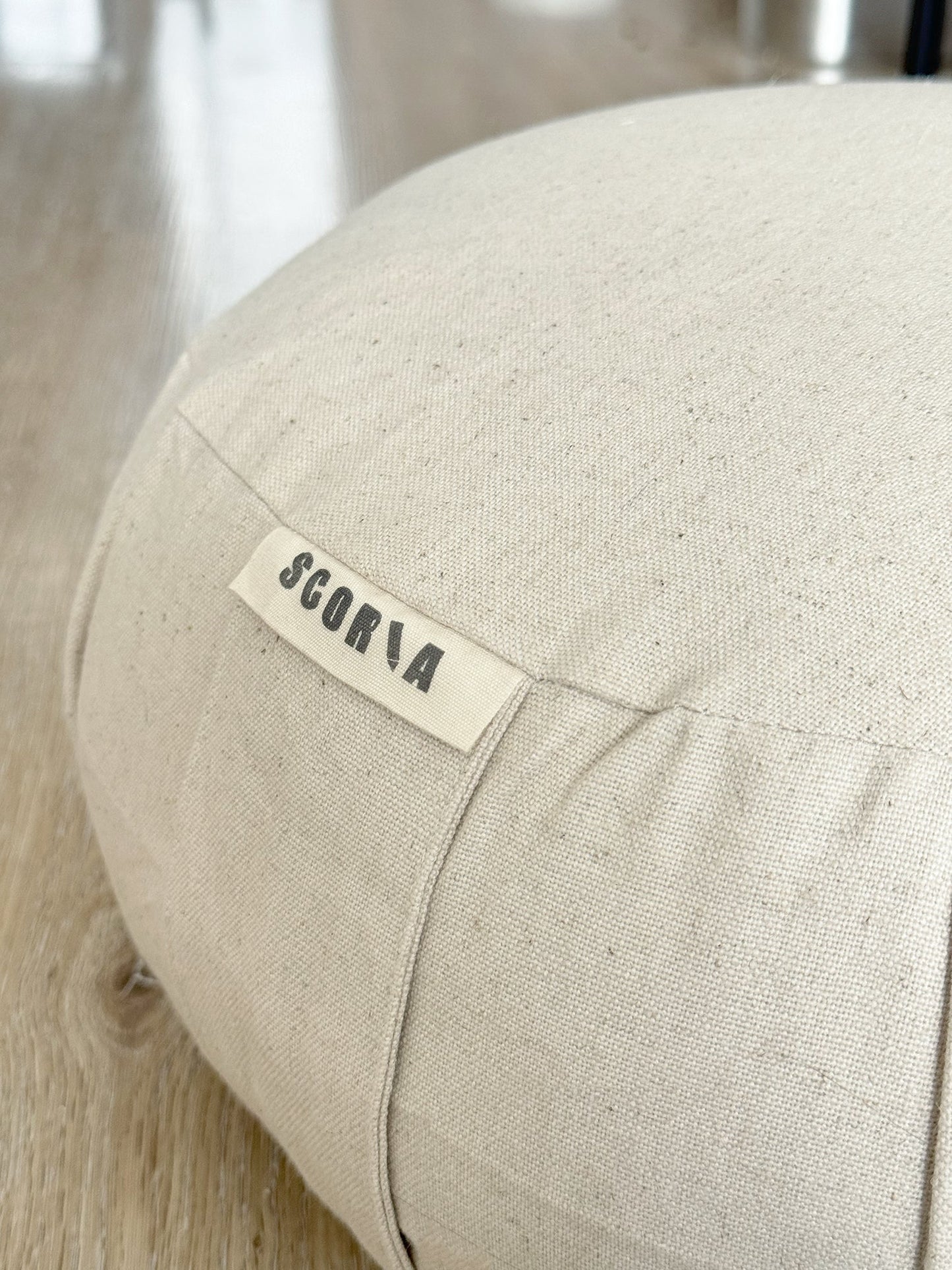 Beige fabric ottoman with a label on a blurred background