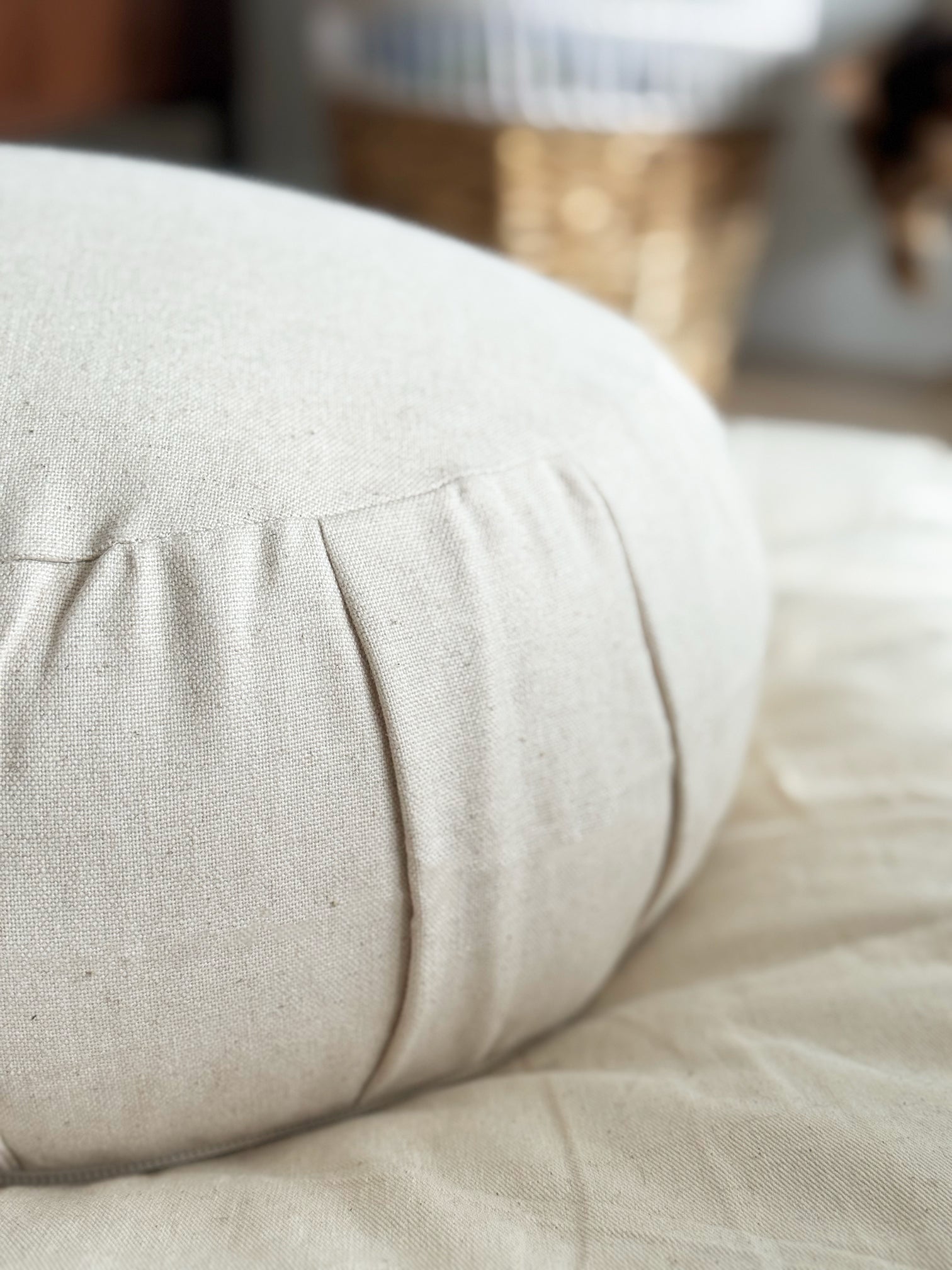 Close-up of a beige cushion on a bed with a blurred background