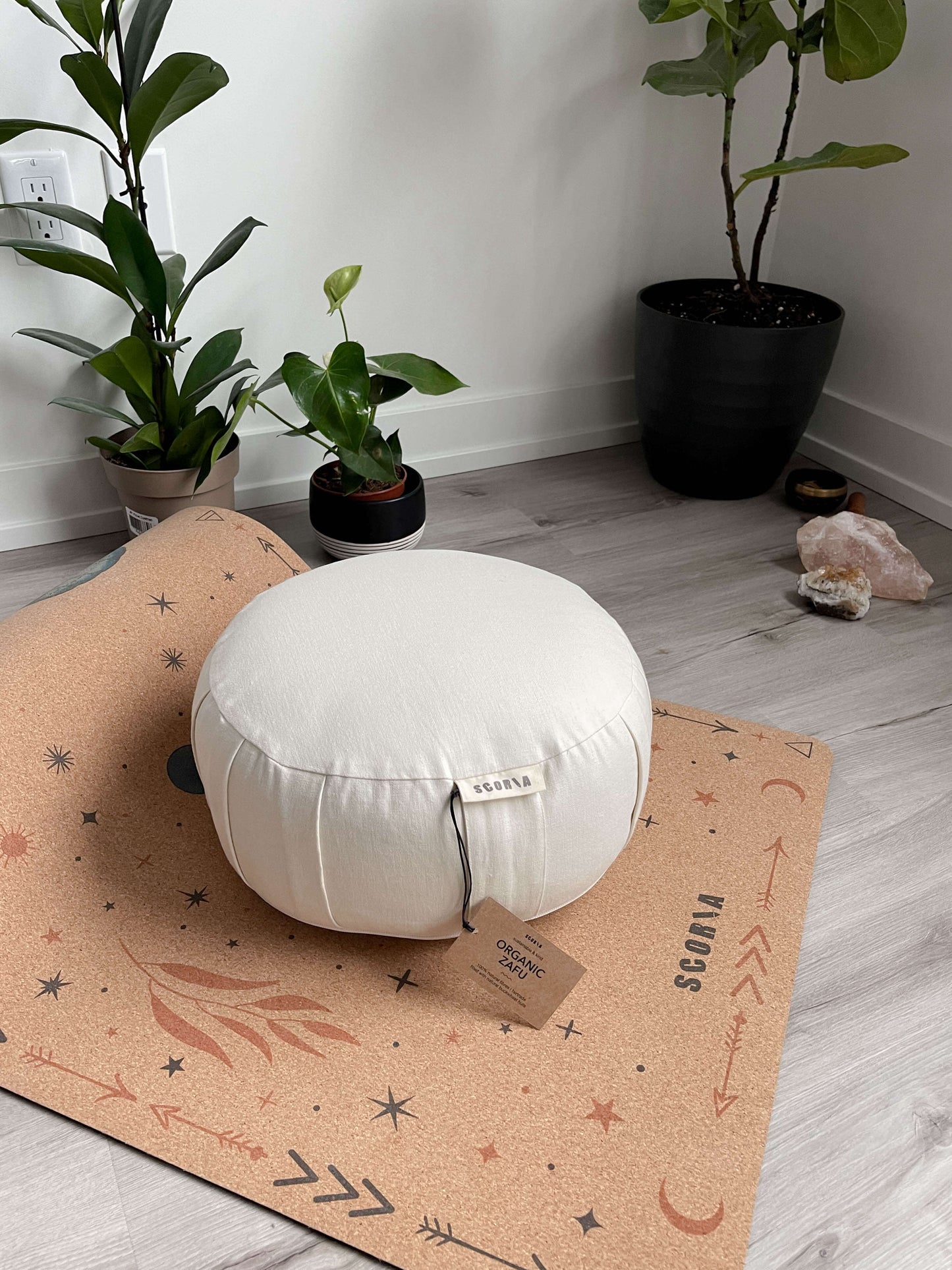 White round meditation pillow on a patterned mat with plants in the background