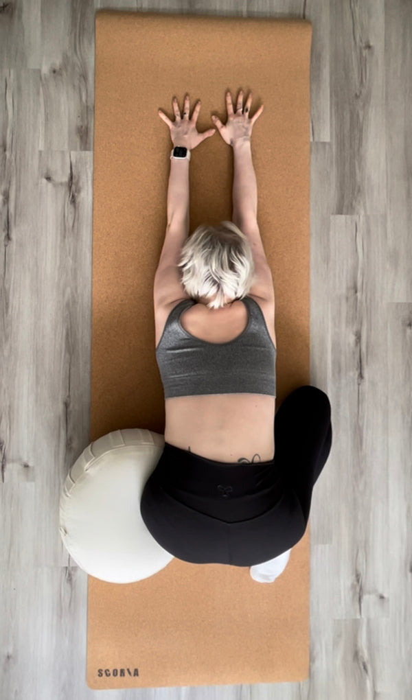 Person stretching on extra tall cork yoga mat with a ball on a wooden floor